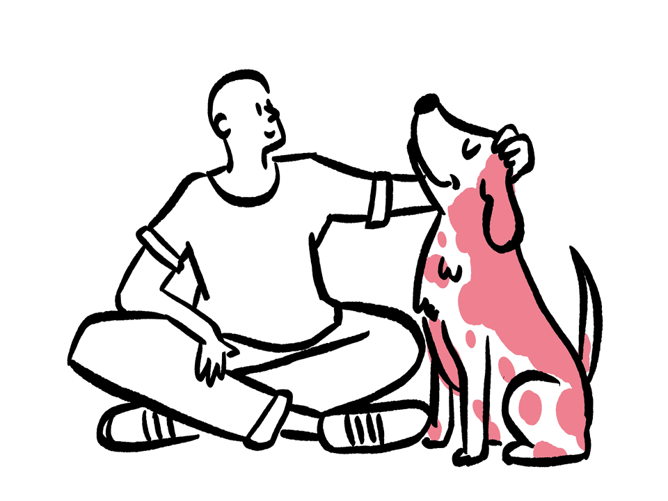 A person petting a dog on the floor.